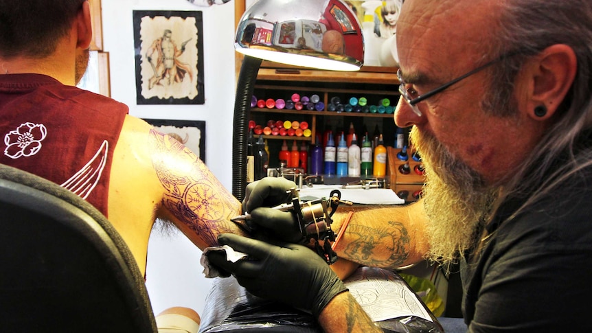 Man tattooing man in studio