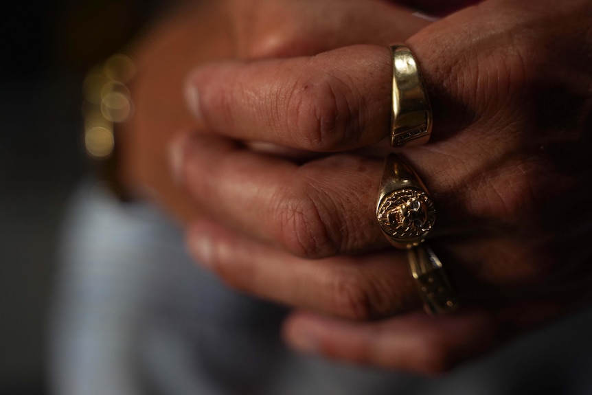 A close up of gold rings on clasped hands. 