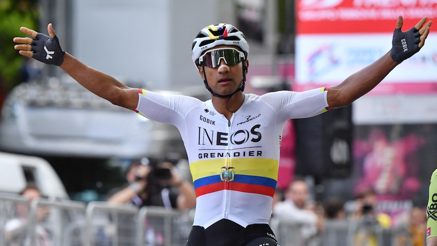 Professional cyclist Jhonatan Narvaez raises his arms, on his bike, celebratating a race win