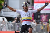 Professional cyclist Jhonatan Narvaez raises his arms, on his bike, celebratating a race win