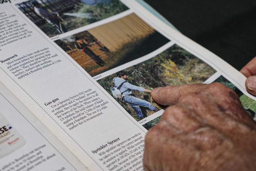 A hand points at a photo of a man spraying Roundup wearing no gloves or face mask, from a brochure made in the 1990s.