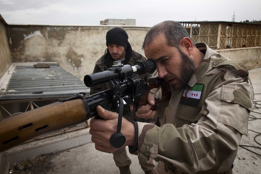 A man wearing a camouflage uniform holds aims a gun