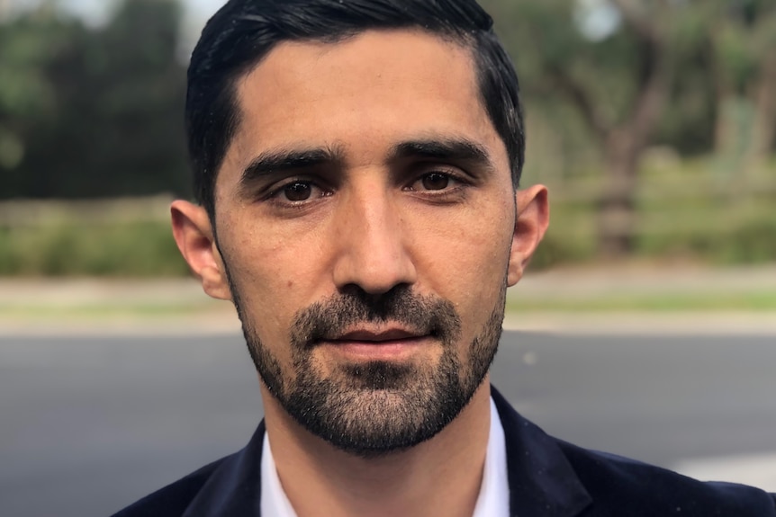 A photo of a man with dark hair and stubble.