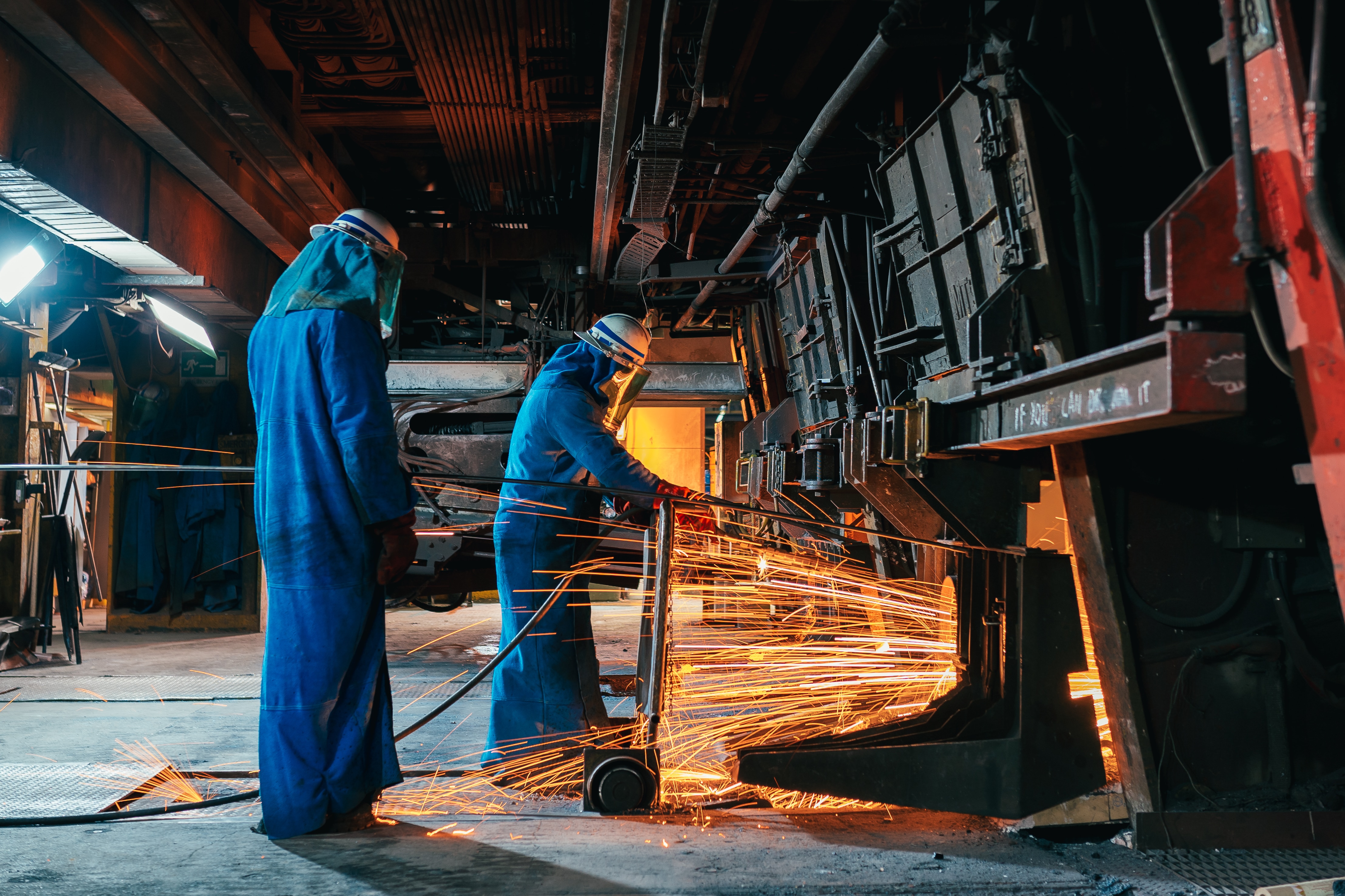 Sparks flying near workers operating near a furnace.  