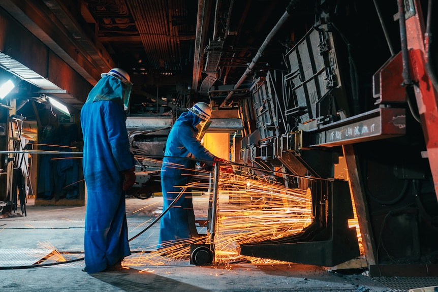 Sparks flying near workers operating near a furnace.  