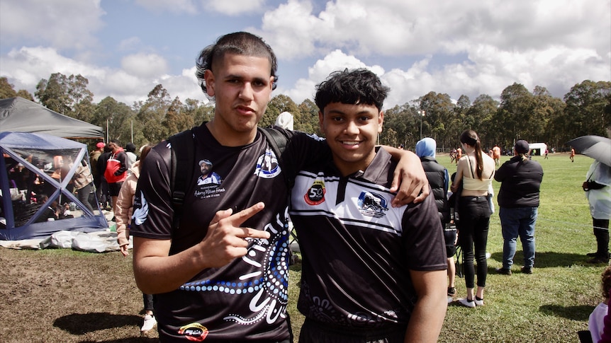 Two men standing in mud wearing black and white football jerseys