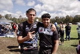Two men standing in mud wearing black and white football jerseys