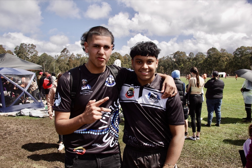 Two men standing in mud wearing black and white football jerseys