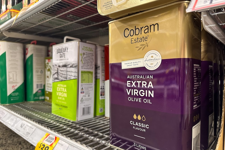 A large metal 3 liter tin of extra virgin olive oil on a supermarket shelf in a purple tin. 