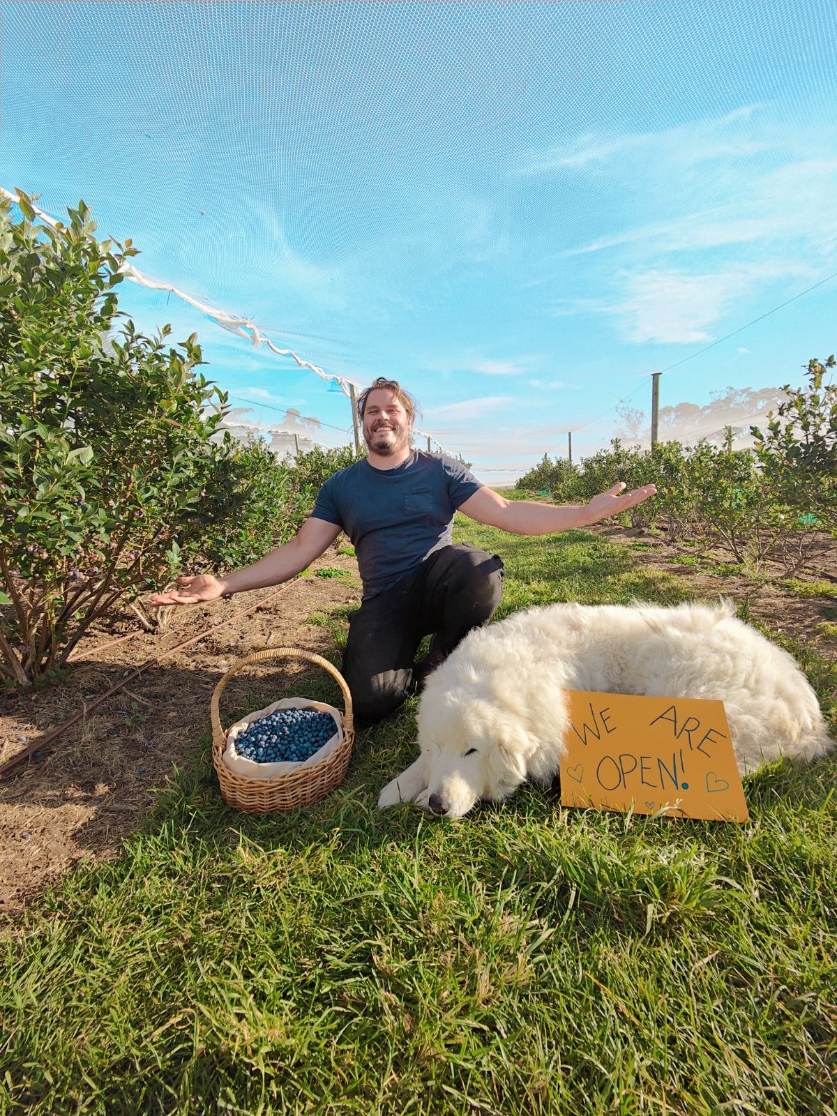 Robert with his dog and a sign reading "we are open"
