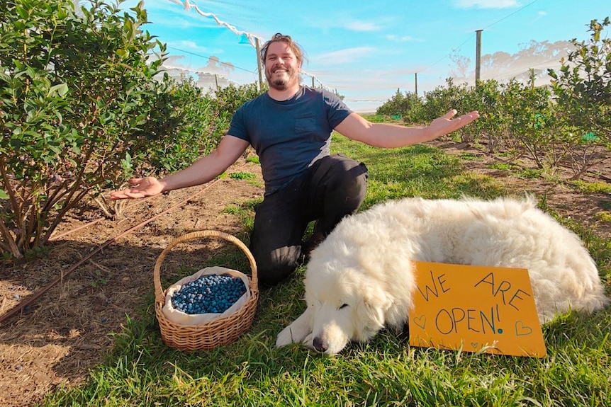 Robert with his dog and a sign reading "we are open"