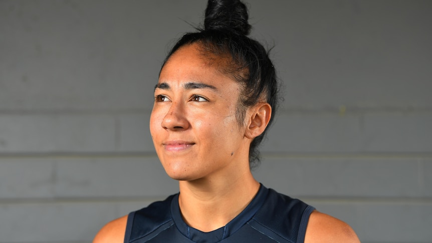 Carlton's Darcy Vescio smiling and looking up, in front of a grey wall at an AFLW press event in 2020