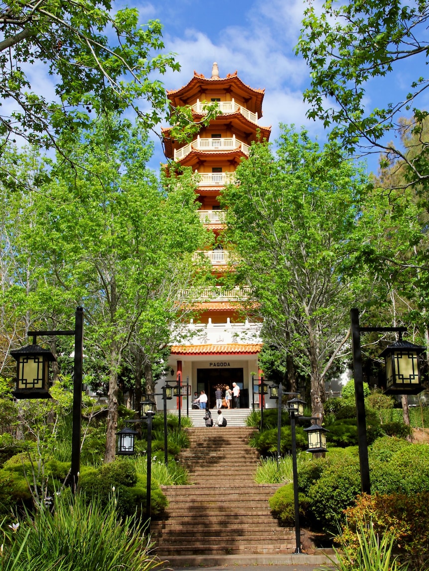 eight-storey pagoda with trees and lanterns in foreground at the top of a flight of outdoor stairs