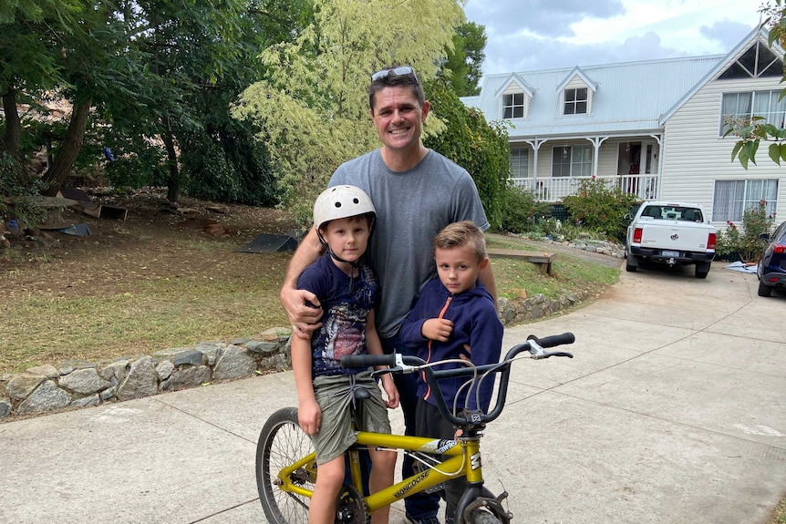 Paul Peacock with his kids on their driveway.