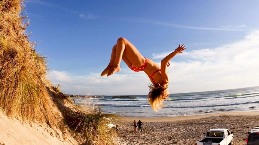 Brooke Mason backflipping on a beach