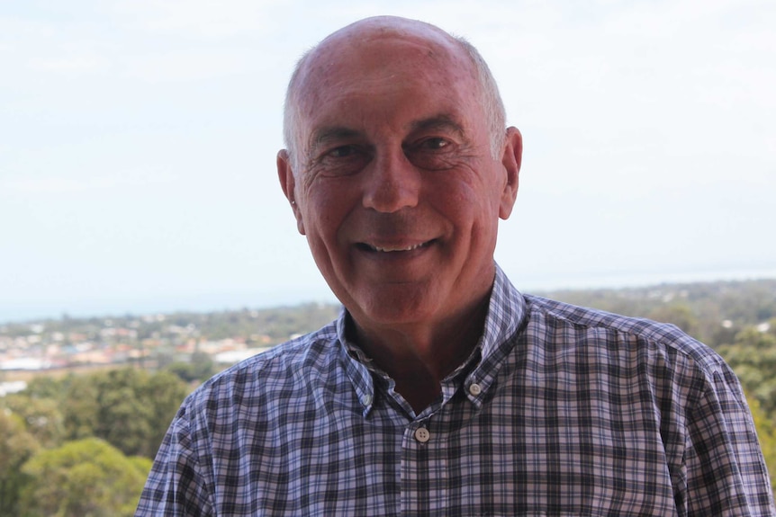 Warren Truss, wearing a checked shirt, smiles at the camera.