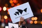 A hand holding a sign that reads "NSW not for sale"