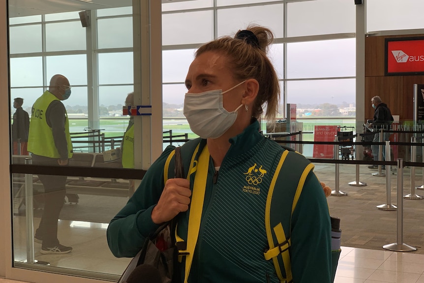 Olympian Bel White wearing a mask, talks to the media in Adelaide Airport.