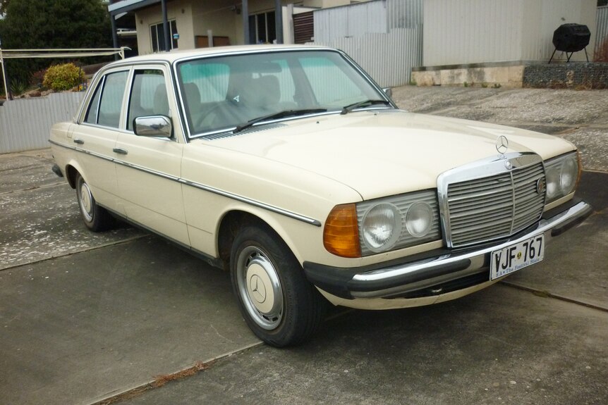 Cream coloured Mercedes Benz on paved area.