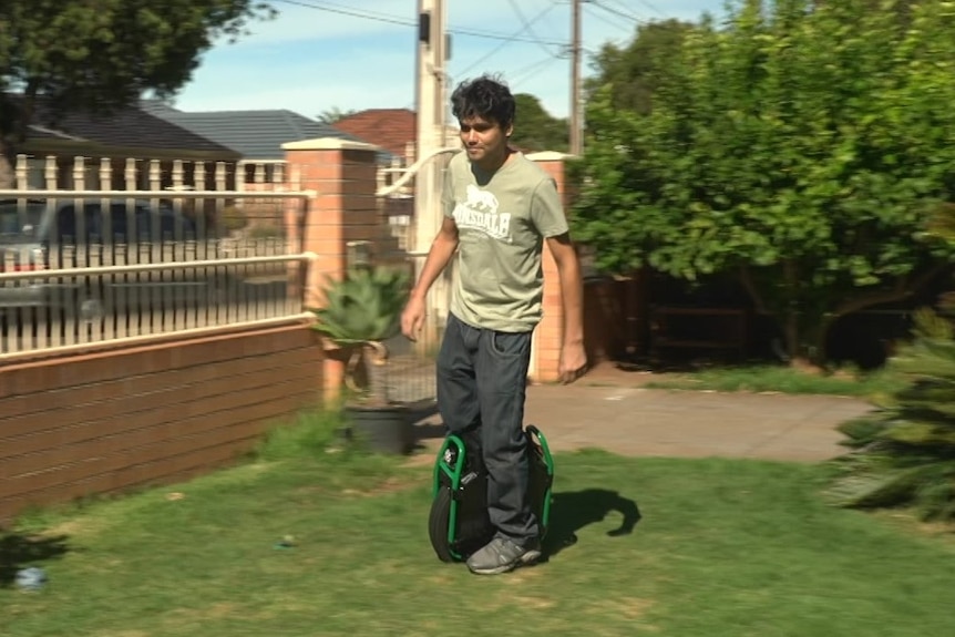 A man riding an electric unicycle without handle bars on a front lawn