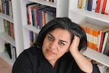 Iranian-Australian writer Shokoofeh Azar resting on her hand, bookcase in the background