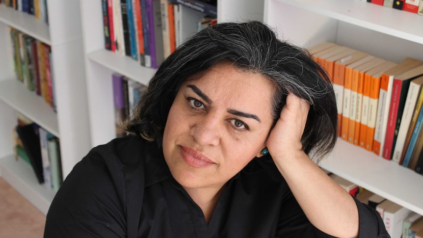 Iranian-Australian writer Shokoofeh Azar resting on her hand, bookcase in the background