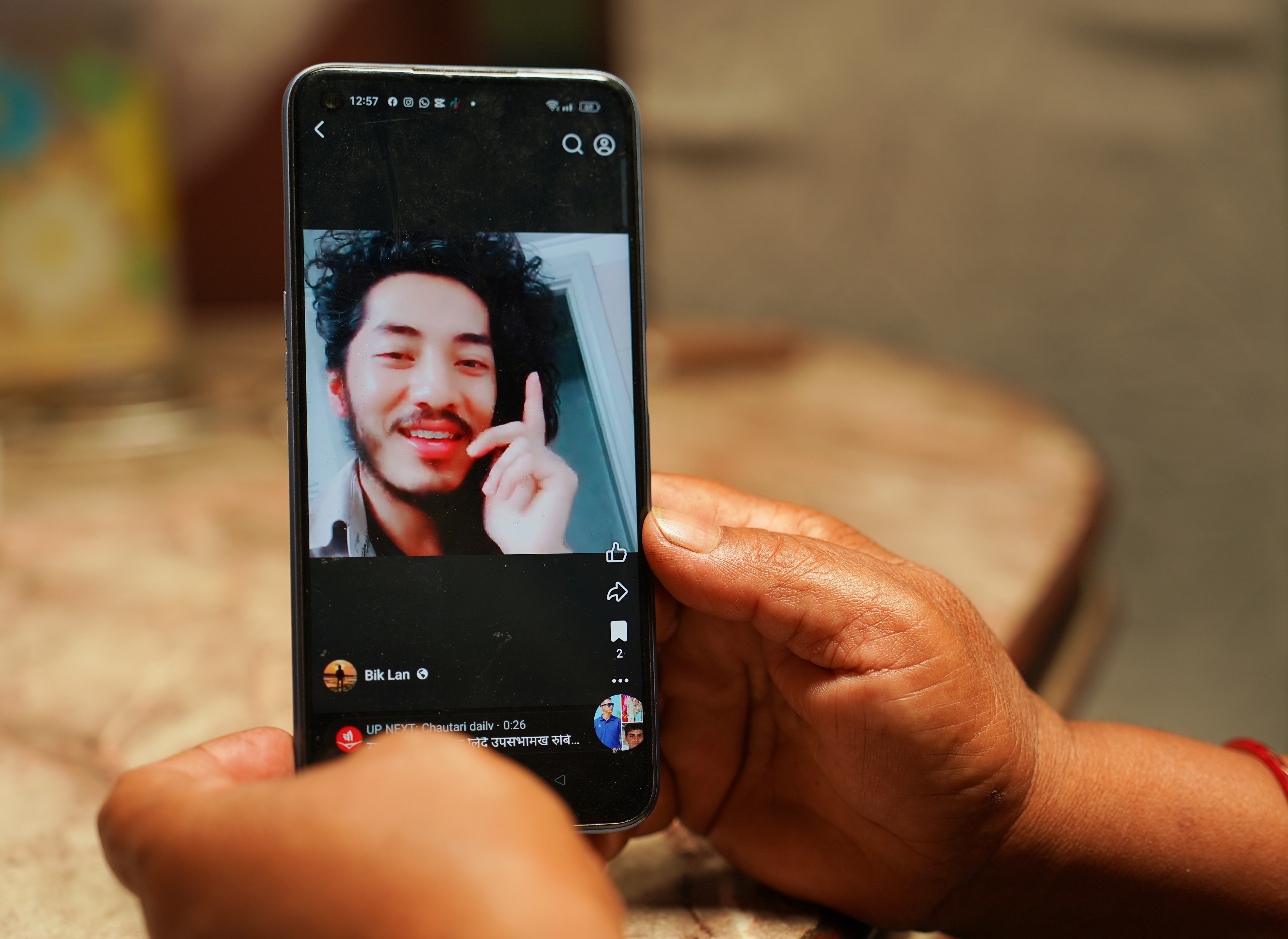 A photo of a smiling man is seen on the screen of a phone.