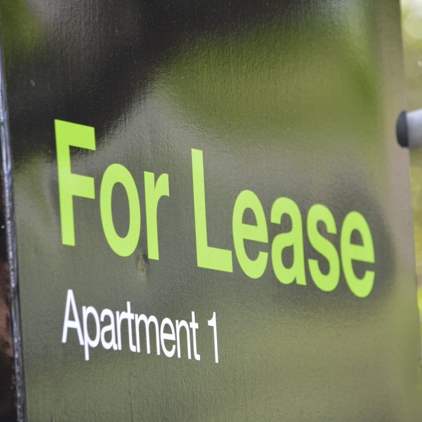 A black sign with green letters reading "For Lease, Apartment 1".