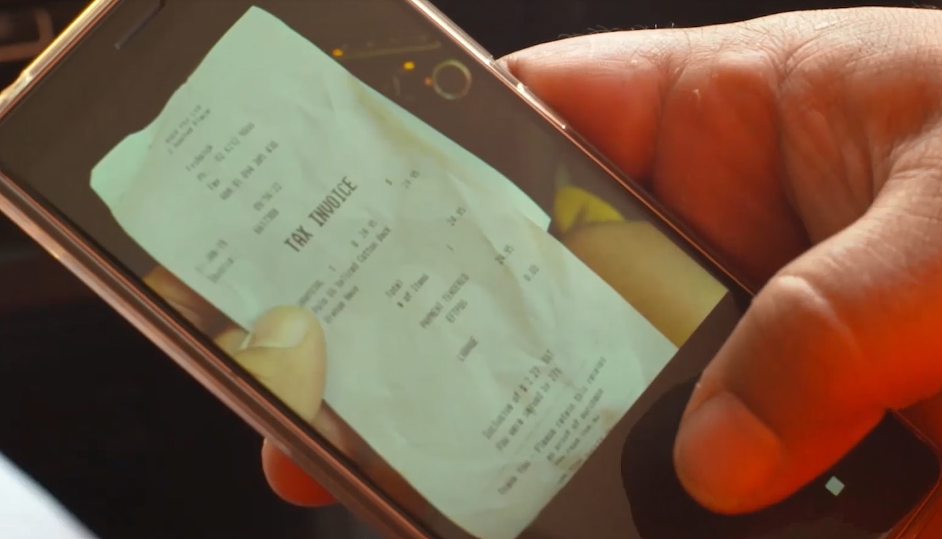 A close up of person taking a photo of a tax invoice on their smartphone
