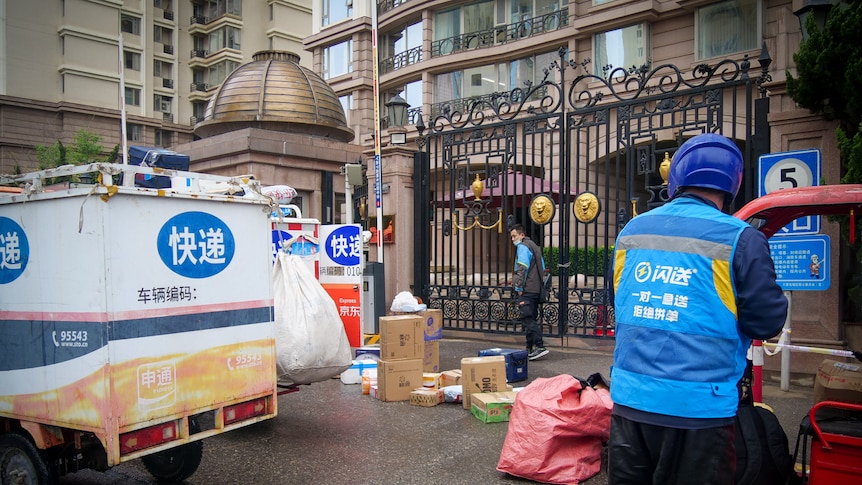 Trucks parked outside an apartment building, with men in bright blue jackets unpacking boxes
