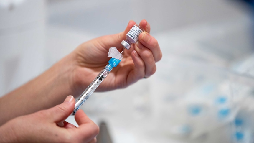 A person draws a syringe of Pfizer coronavirus vaccine in Perth, WA.