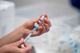 A person draws a syringe of Pfizer coronavirus vaccine.