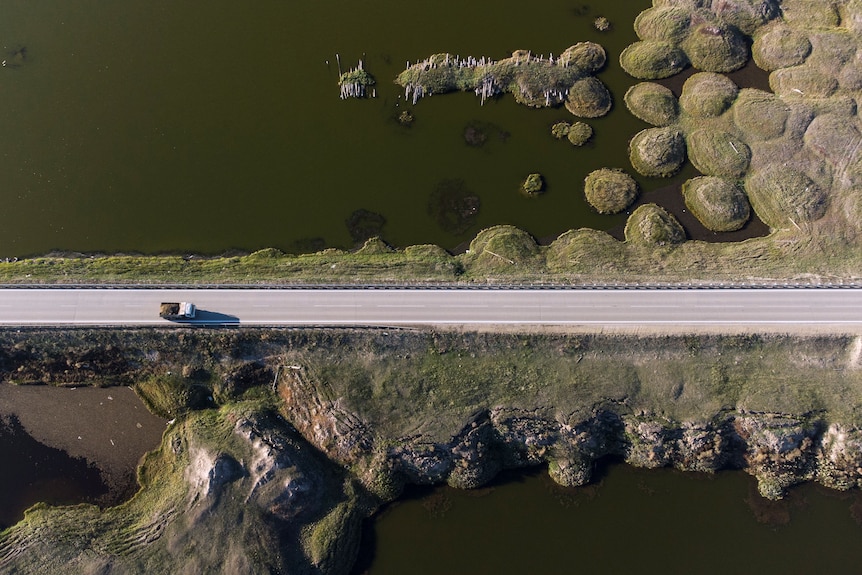an aerial view of a  truck travelling on a road through an area deformed by thawing permafrost