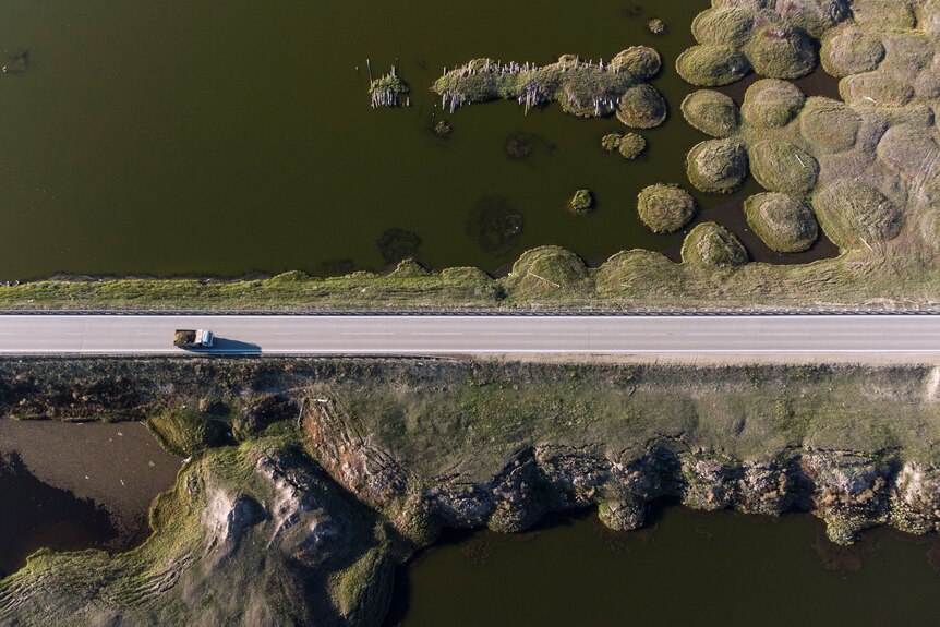 an aerial view of a  truck travelling on a road through an area deformed by thawing permafrost