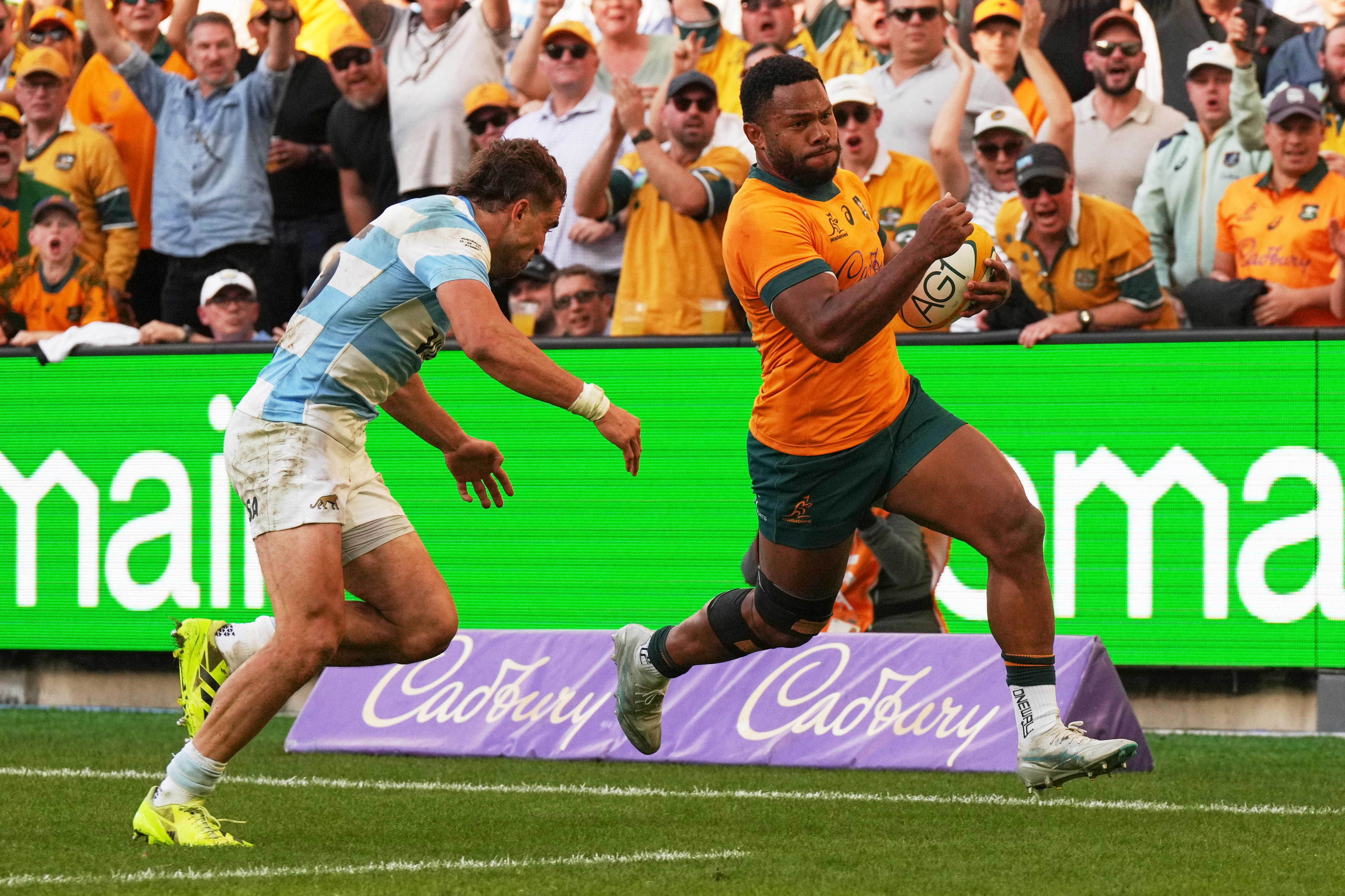 Un jugador de rugby de los Wallabies corre con la pelota y escapa de un tackle de los Pumas para marcar un try.