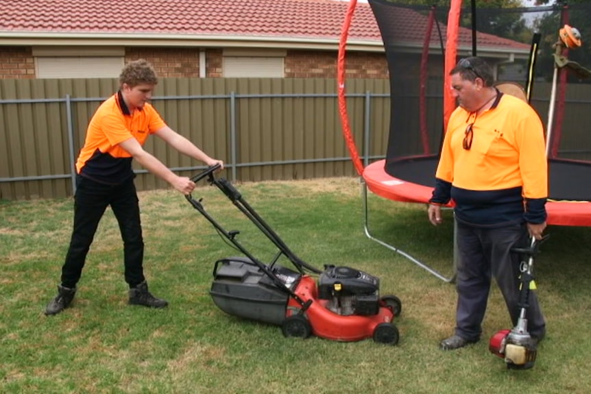 Brodie Lunn mowing lawn with support worker Kerry Wilson