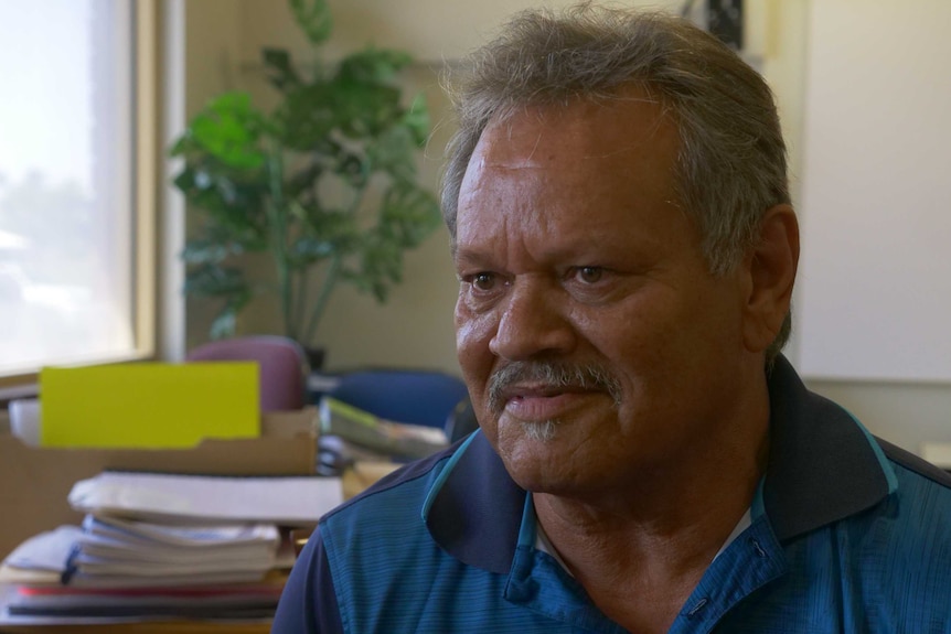 A man sits in his office with a grim look on his face