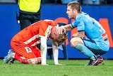 Luke Brattan kneels down in front of Nathaniel Atkinson, who is on his knees