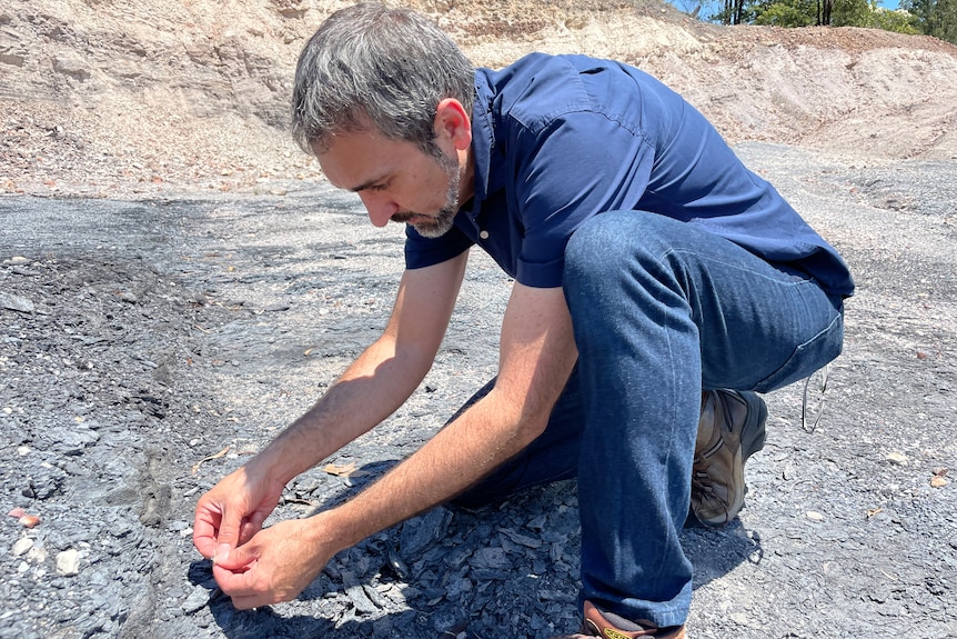 Anthony crouches over a fossil.