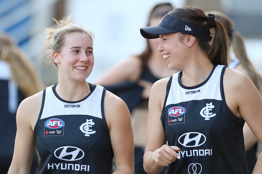 Carlton's Mimi Hill and Brooke Vickers smiling at one another at an AFLW training session in 2021.