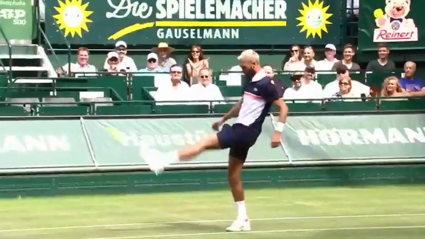 Benoit Paire kicks a yellow tennis ball with his left foot