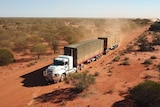 A convoy of trucks drive along a dusty road