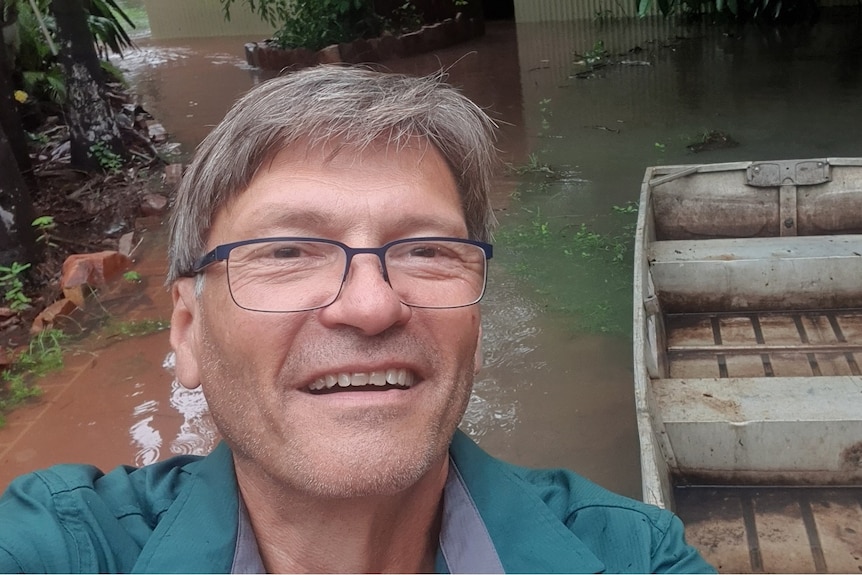 A man taking a selfie in front of floodwater.