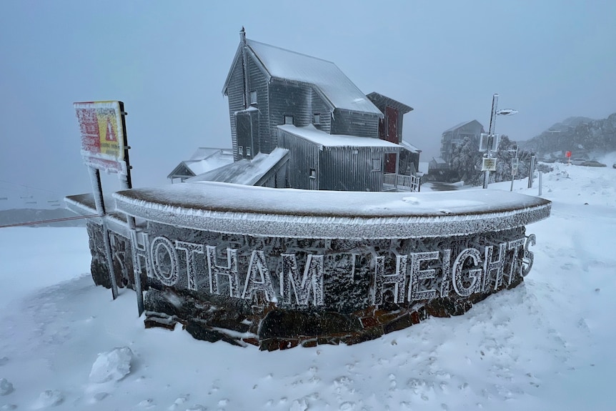 A big sign saying Hotham Heights and a wooden building covered in ice and snow