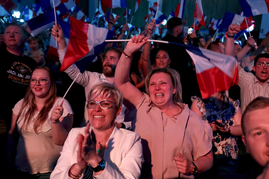 A crowd waves french flags and celebrates 
