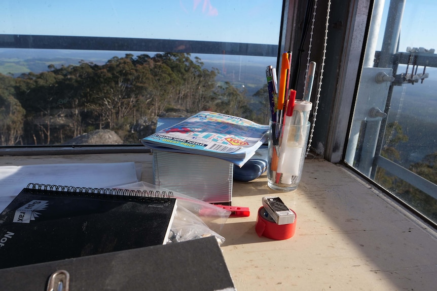 A desk in a tower up high, showing a word search and pens