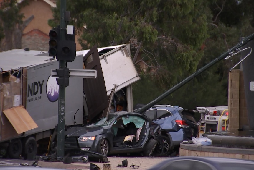 the aftermath of a crash site involving a truck and two cars all damaged