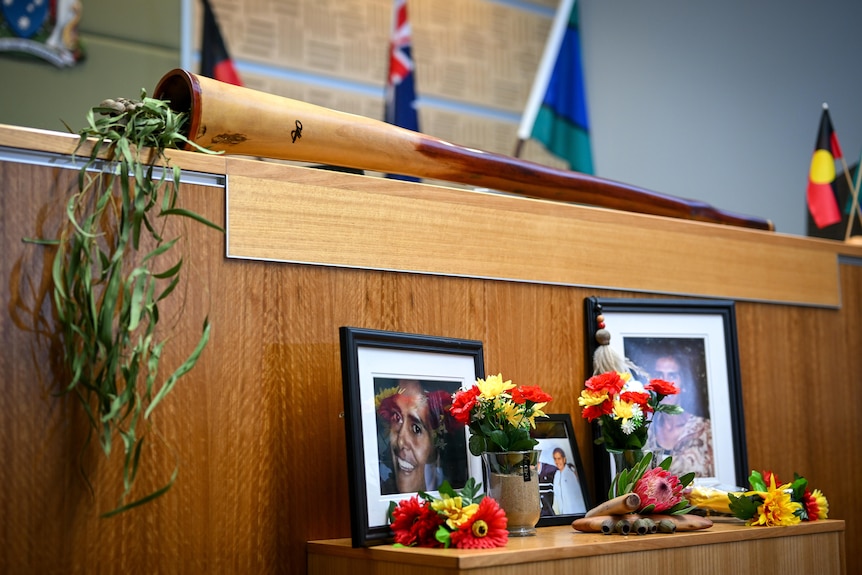 Several framed photos of Veronica Nelson and family sit among red, yellow and black floral decorations.