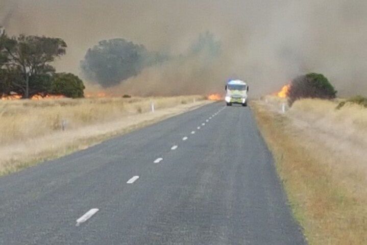 A CFS truck driving along the road with a fire burning behind