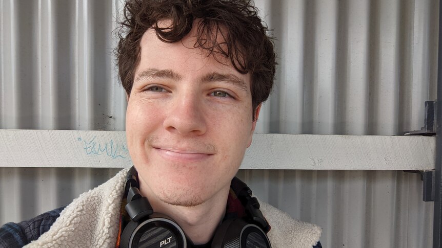 A young man smiling in a selfie, in a story about phone calls making you anxious.